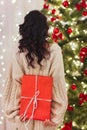 Back of Woman Holding Gift Box with Present at Home Near Christmas Tree Royalty Free Stock Photo