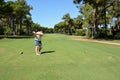 A young Caucasian woman hits a golf ball near the hole. In the background, in the perspective, is the glade of a private golf club Royalty Free Stock Photo