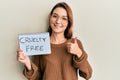 Young caucasian woman holding cruelty free message paper smiling happy and positive, thumb up doing excellent and approval sign