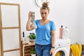 Young caucasian woman holding dirty sock at laundry room depressed and worry for distress, crying angry and afraid Royalty Free Stock Photo