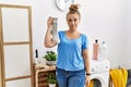 Young caucasian woman holding dirty sock at laundry room relaxed with serious expression on face Royalty Free Stock Photo