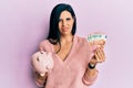 Young caucasian woman holding euro banknotes and piggy bank clueless and confused expression Royalty Free Stock Photo