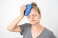 Young caucasian woman holding ice bag to her head, suffering from a headache or fever