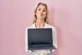 Young caucasian woman holding laptop showing screen looking at the camera blowing a kiss being lovely and sexy Royalty Free Stock Photo