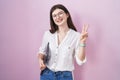 Young caucasian woman holding laptop smiling looking to the camera showing fingers doing victory sign Royalty Free Stock Photo