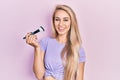 Young caucasian woman holding makeup brush looking positive and happy standing and smiling with a confident smile showing teeth Royalty Free Stock Photo