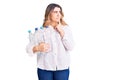Young caucasian woman holding recycling plastic bottles serious face thinking about question with hand on chin, thoughtful about Royalty Free Stock Photo