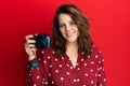 Young caucasian woman holding reflex camera looking positive and happy standing and smiling with a confident smile showing teeth Royalty Free Stock Photo