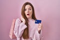 Young caucasian woman holding shopping bag and credit card afraid and shocked with surprise and amazed expression, fear and Royalty Free Stock Photo