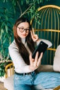 Young caucasian woman holding smartphone looking on cell using mobile phone technology at home taking selfie for social media or Royalty Free Stock Photo