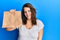 Young caucasian woman holding take away paper bag looking positive and happy standing and smiling with a confident smile showing Royalty Free Stock Photo
