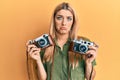 Young caucasian woman holding vintage camera depressed and worry for distress, crying angry and afraid Royalty Free Stock Photo