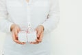 Young caucasian woman holds in hands gift box tied with striped red twine. White wall background. Christmas New Years presents Royalty Free Stock Photo