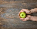 Young caucasian woman holds in hands ripe red apple on dark plank wood background. Thanksgiving autumns harvest gratefulness Royalty Free Stock Photo