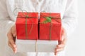 Young Caucasian woman holds in hands stack of gift boxes in white red paper with green twine. Christmas New Years presents