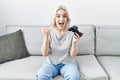 Young caucasian woman at home playing video game holding controller pointing thumb up to the side smiling happy with open mouth Royalty Free Stock Photo