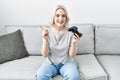 Young caucasian woman at home playing video game holding controller smiling happy pointing with hand and finger to the side Royalty Free Stock Photo