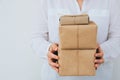 Young caucasian woman in jeans shirt holds in hands stacked gift boxes wrapped in brown craft paper tied with twine. Christmas Royalty Free Stock Photo