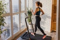 Woman jogging on the modern compact treadmill at her home