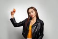 A young Caucasian woman in a leather jacket, holding chicken eggs in her hand. Gray background. Copy space. Feminism, girl power,