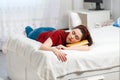 A young Caucasian woman lies on a bed and sleeps with a book under her head. Close up. White interior of the room on the Royalty Free Stock Photo