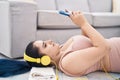 Young caucasian woman listening to music lying on floor at home Royalty Free Stock Photo