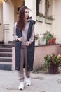 young caucasian woman with long curly brown hair in hoodie suit and dawn vest full body photo on mansion background Royalty Free Stock Photo