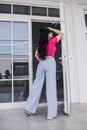 young caucasian woman with long dark wavy hair poses for the camera near the door in warm weather Royalty Free Stock Photo