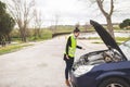 Young Caucasian woman looking at car engine, she doesn`t know what to do, car broken down in the middle of the road. Automobile Royalty Free Stock Photo