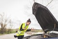 Young Caucasian woman looking at car engine, she doesn`t know what to do, car broken down in the middle of the road. Automobile Royalty Free Stock Photo