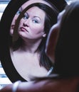 Young Caucasian woman looking at herself in vanity mirror checking her hair and makeup Royalty Free Stock Photo