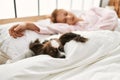 Young caucasian woman lying on bed with dog sleeping at bedroom Royalty Free Stock Photo