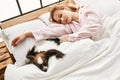 Young caucasian woman lying on bed with dog sleeping at bedroom Royalty Free Stock Photo