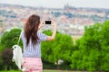 Young caucasian woman making photo of european old city by mobile phone from the observation place Royalty Free Stock Photo