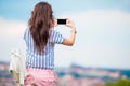 Young caucasian woman making photo of european old city by mobile phone from the observation place Royalty Free Stock Photo