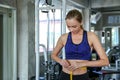 Young caucasian woman measuring waist in gym. Slim woman measuring her thin waist with a tape measure. smiling people with measure