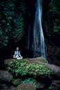 Young Caucasian woman meditating, practicing yoga at waterfall. Gyan mudra. Leke Leke waterfall, Bali, Indonesia Royalty Free Stock Photo