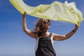 Young caucasian woman outdoors playing with yellow scarf on a windy and sunny day. Lifestyle and summertime