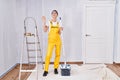 Young caucasian woman painting walls waiving saying hello happy and smiling, friendly welcome gesture