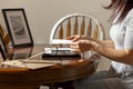 A young caucasian woman is placing a printed photograph into a picture frame with kickstand.