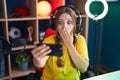 Young caucasian woman playing video games with smartphone covering mouth with hand, shocked and afraid for mistake Royalty Free Stock Photo