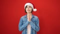 Young caucasian woman praying wearing christmas hat over isolated red background Royalty Free Stock Photo