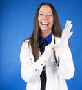 Young caucasian woman puting in gloves smiling on blue background, virus protection hygiene concept