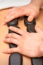 Young caucasian woman receiving back massage with black stones by masseur in spa salon. A woman getting a spa treatment. Royalty Free Stock Photo