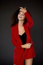 young caucasian woman in red clothes in a dark studio, a curly-haired brown-eyed european woman in bright clothes