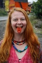 A young Caucasian woman with red hair chews traditional Asian tobacco - betel leaves, which makes her mouth bright red.