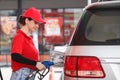 Young caucasian woman red uniform holding fuel pump nozzle service refuel gas station. oil power energy automobile transport Royalty Free Stock Photo