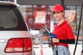 Young caucasian woman red uniform holding fuel pump nozzle service refuel gas station. oil power energy automobile transport Royalty Free Stock Photo