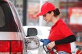 Young caucasian woman red uniform holding fuel pump nozzle service refuel gas station. oil power energy automobile transport Royalty Free Stock Photo