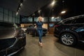 Young caucasian woman rejoices buying a car in a car dealership.